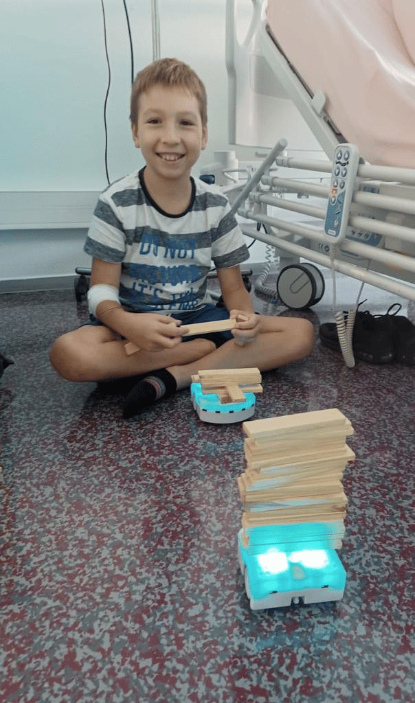 Enfant malade qui joue avec des robots Thymio dans un hôpital